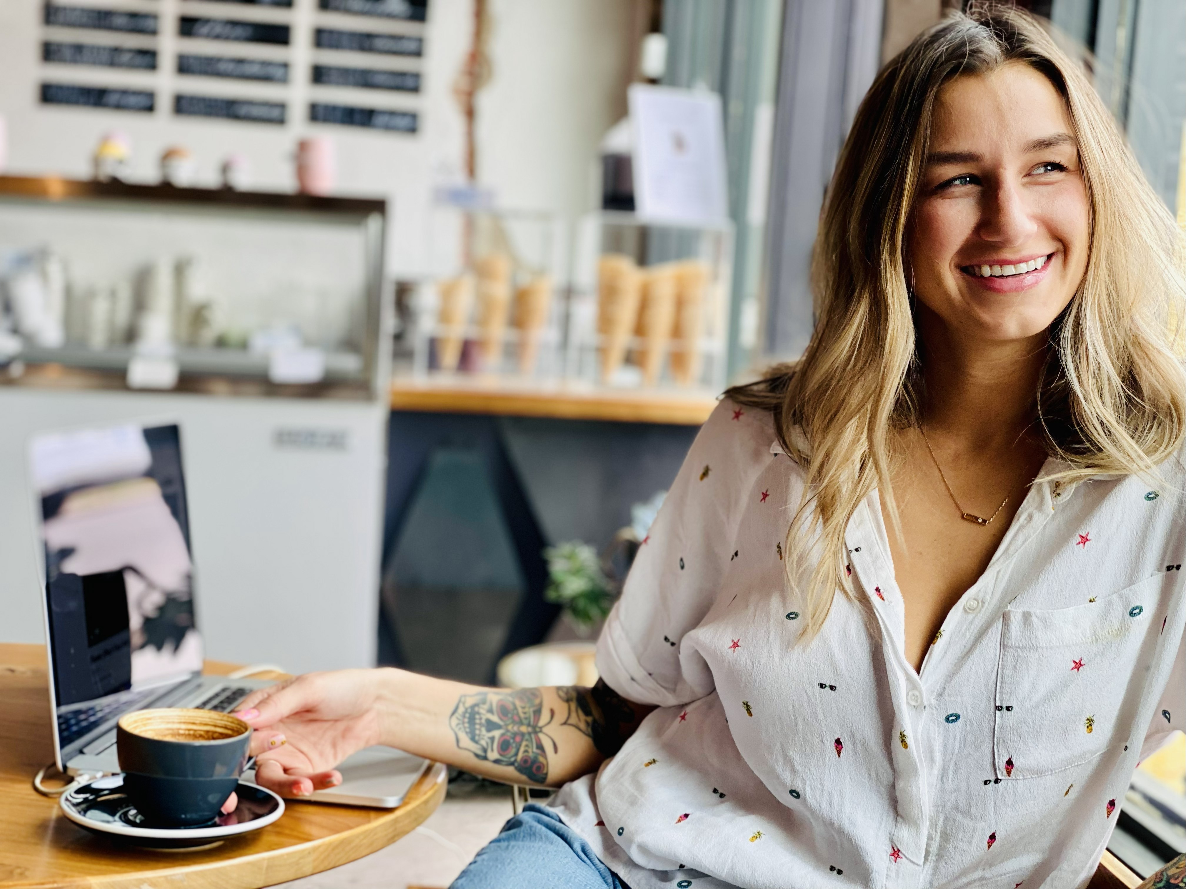 Image of a woman sitting at a table, drinking coffee