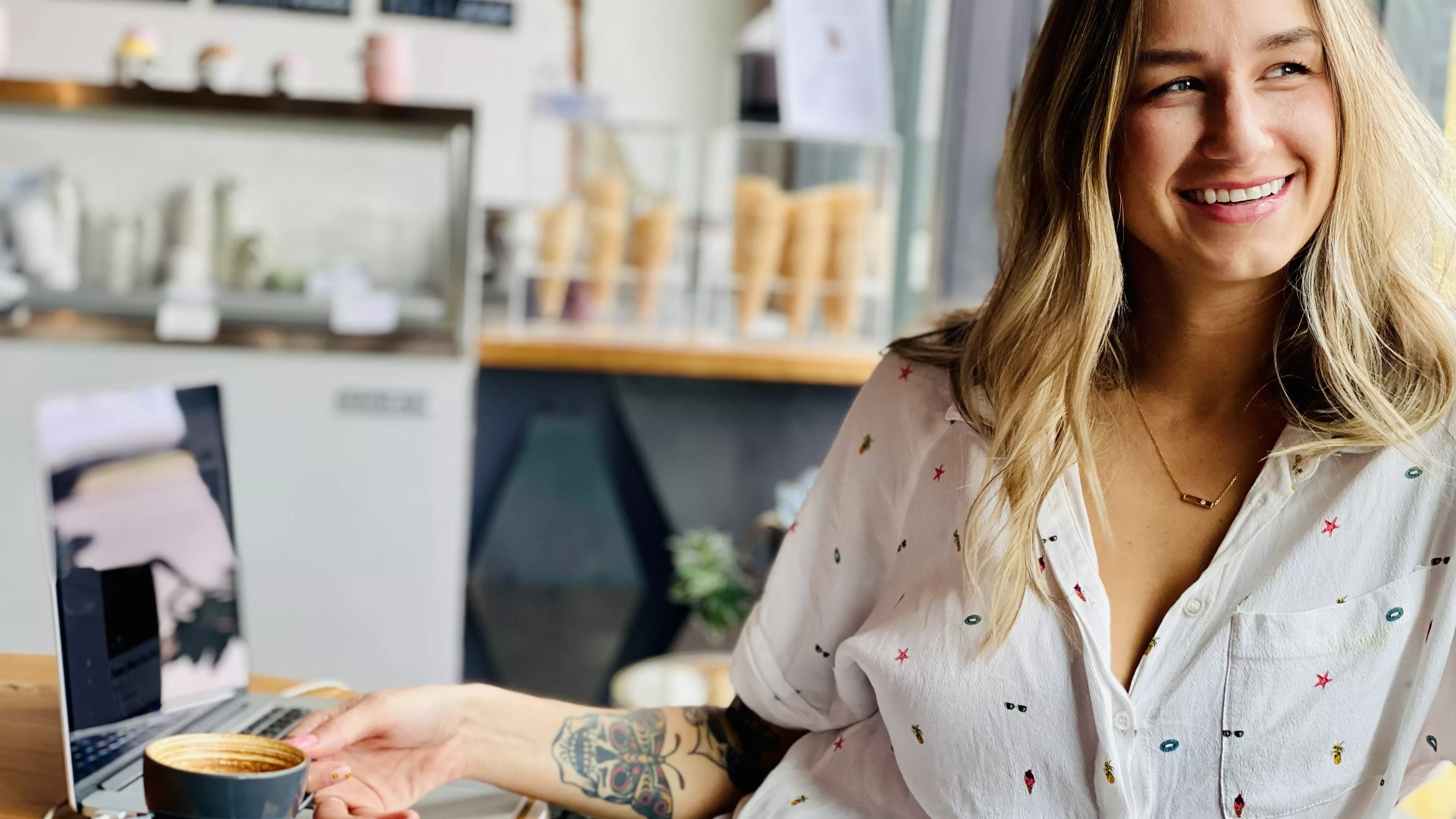 Image of a woman sitting at a table, drinking coffee
